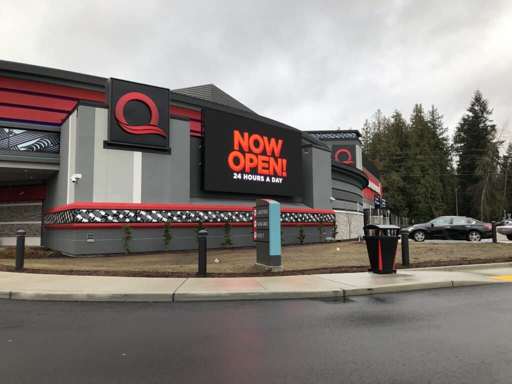 Quil Ceda Creek Casino exterior corner with illuminated “Now Open” digital signage on the building facade.