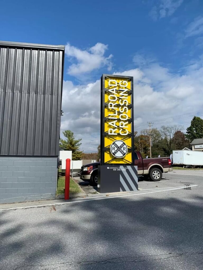 Bold yellow and black exterior wayfinding tower sign for a commercial property, designed by Gable.