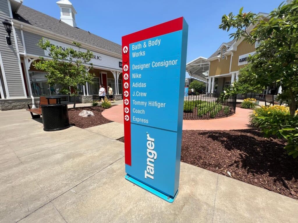 Tanger Outlets tenant directory monument sign listing retail stores in an outdoor shopping center.