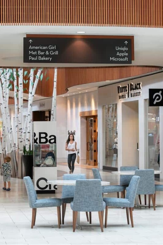 Overhead retail wayfinding sign inside a shopping mall directing visitors to major stores and dining by Gable.