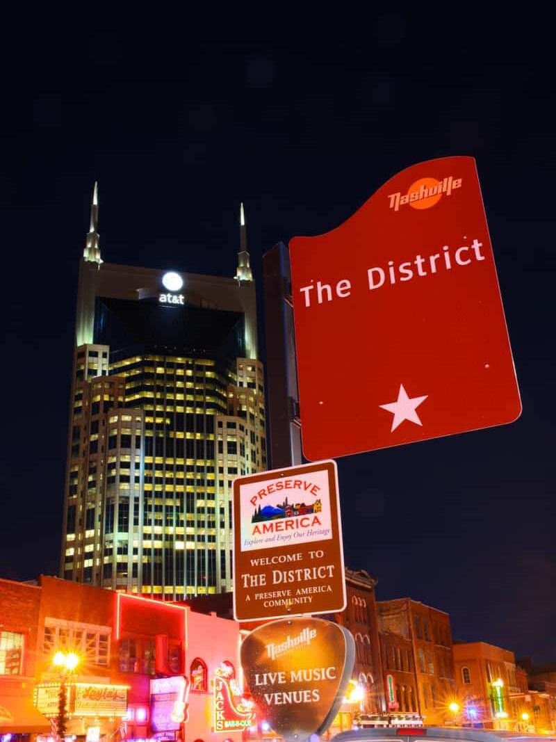 The District wayfinding sign in downtown Nashville at night with illuminated streetscape context and signage by Gable.