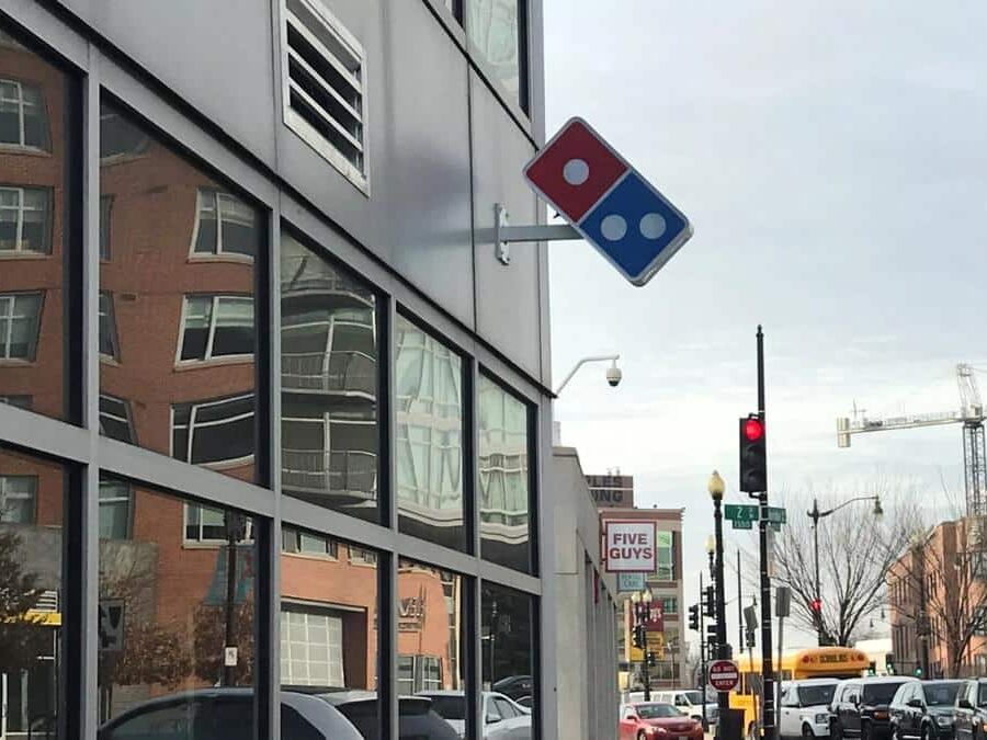 Domino’s blade sign mounted on an urban storefront with custom exterior branding by Gable.