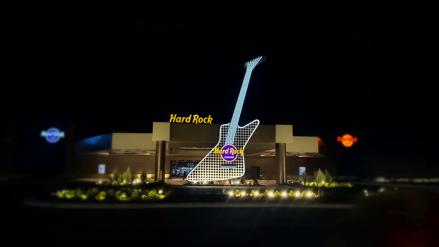 Hard Rock Hotel & Casino exterior at night with illuminated oversized guitar monument sign at the main entrance.