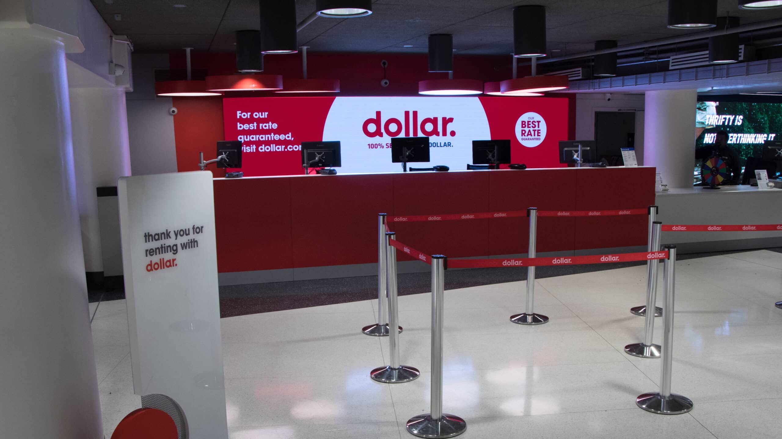 Dollar rental car airport counter with bold branded wall graphics and service area signage by Gable visual communications.