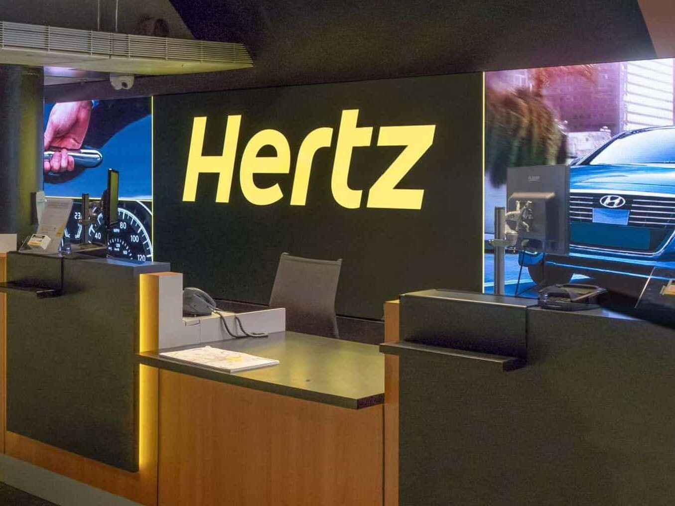 Hertz rental car counter at Ronald Reagan Airport featuring illuminated branded signage and customer service graphics by Gable.