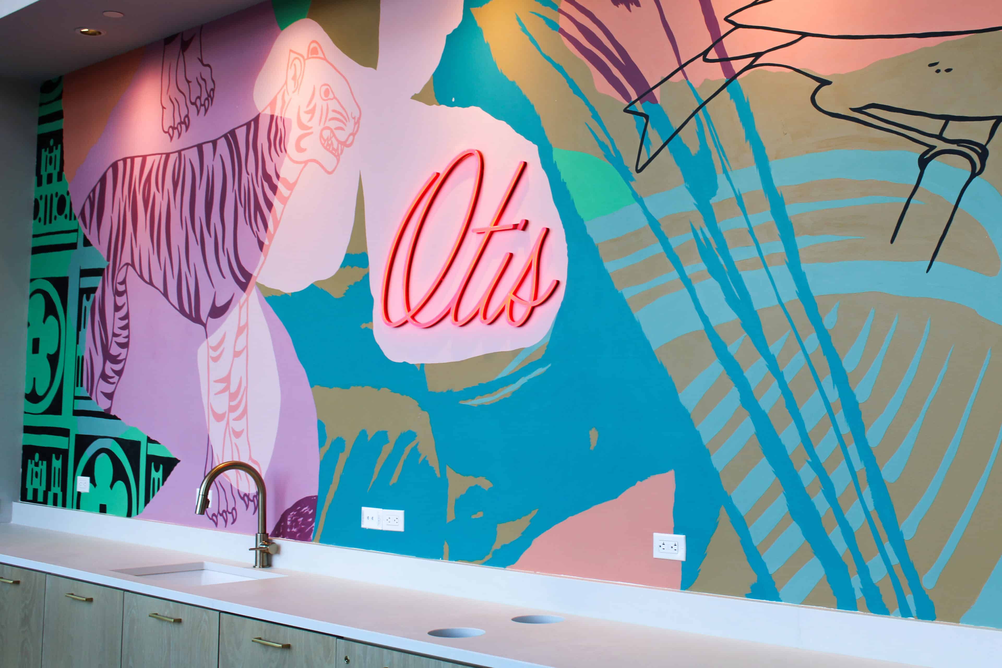 Otis branded interior mural wall with illuminated script signage in a modern residential amenity space.