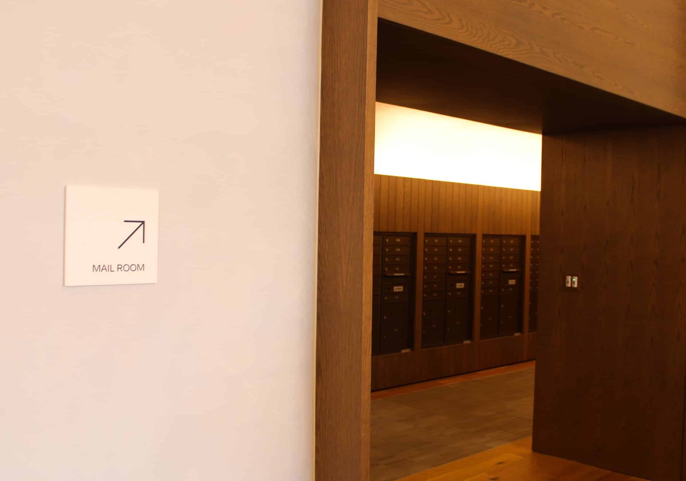 Accessible interior wayfinding plaque mounted beside a hallway entrance in a modern apartment development.