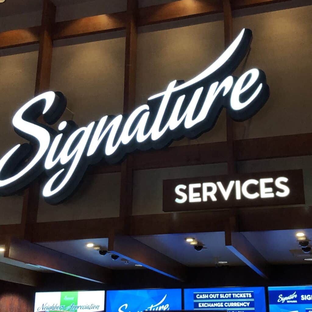 Signature Services interior sign with illuminated lettering and branded guest experience graphics by Gable.