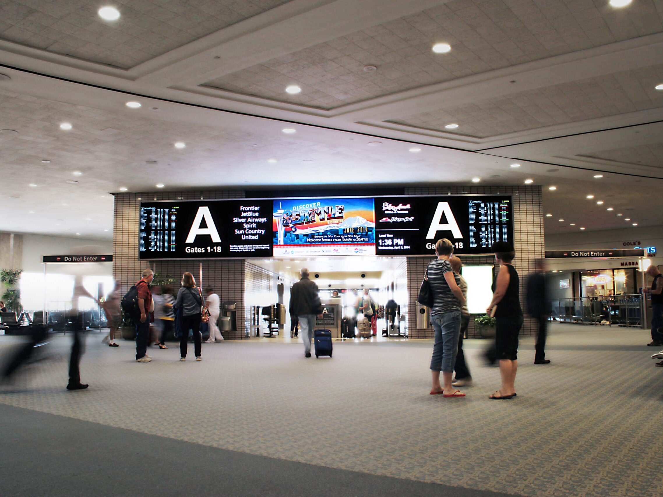 Airport concourse with large digital flight information displays and terminal wayfinding signage by Gable.