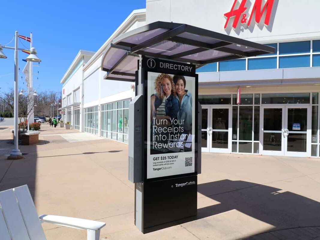 Mall directory and advertising kiosk outside H&M in an outdoor lifestyle shopping center.